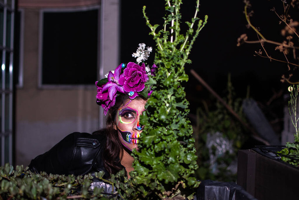 retrato de mulher vestindo uma maquiagem Dia de muertos atrás de uma planta de alface - Foto, Imagem