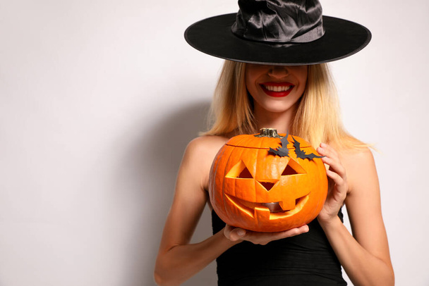 Mulher bonita em traje de bruxa com jack o 'lanterna no fundo branco. Festa de Halloween - Foto, Imagem