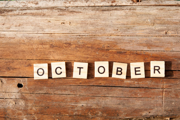 The word october is written in wooden letters on a wooden background. Autumn concept and calendar concept. Copy space - Фото, изображение
