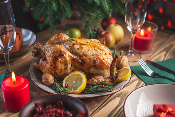 Crispy baked chicken with rosemary and berries on a wooden table. Traditional Christmas dish for a festive dinner in a rustic style - Photo, image
