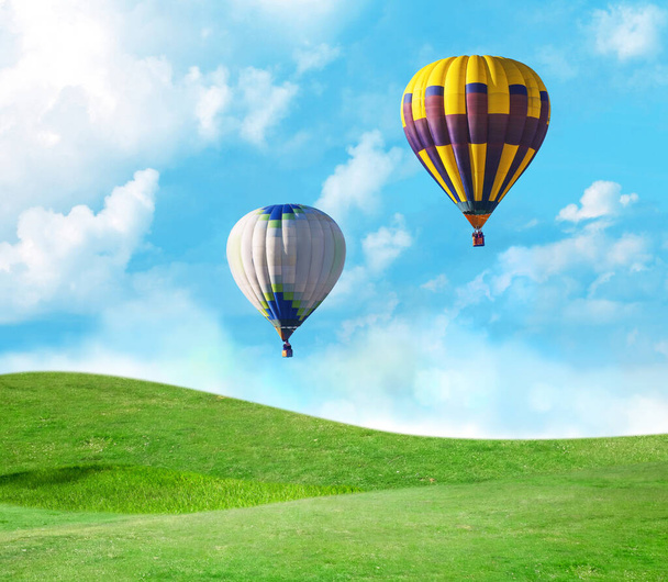 Φανταστικά όνειρα. Μπαλόνια θερμού αέρα σε μπλε ουρανό με σύννεφα πάνω από το πράσινο λιβάδι  - Φωτογραφία, εικόνα