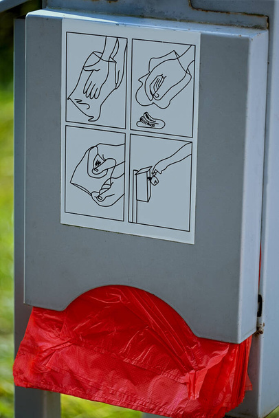 bolsas de caca de perro rojo en una caja de metal gris e ilustración explicativa - Foto, Imagen