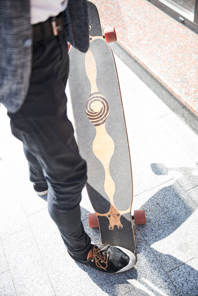 Stylish man stepping on a cool longboard - Foto, Imagen