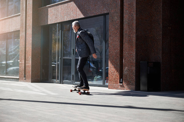 Stylish gentleman riding a longboard through the street - Foto, Imagem