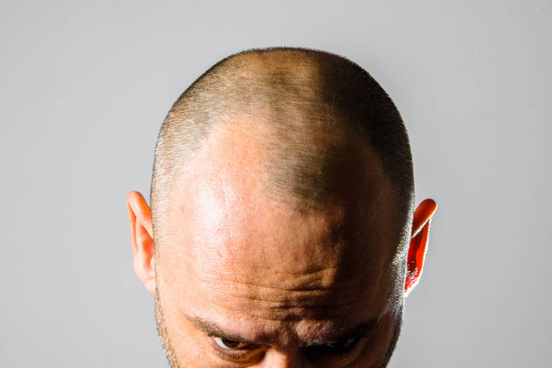 Чоловік показує свою лисого поголену голову в студії
. - Фото, зображення