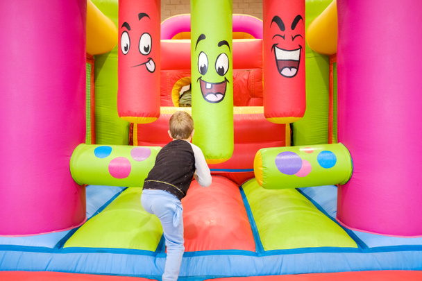 Παιδί έχει τη διασκέδαση πηδώντας σε ένα φουσκωτό κάστρο σε μια παιδική έκθεση. - Φωτογραφία, εικόνα