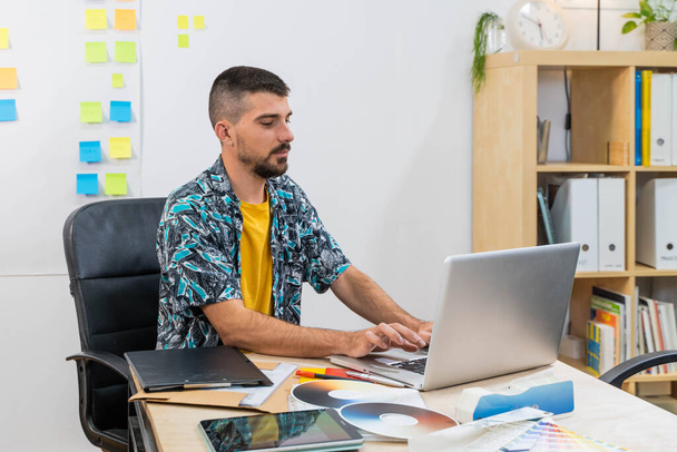 Casual business man in startup office working on laptop. Business man with post it stickers background. Creative studio. Man in modern office. - 写真・画像