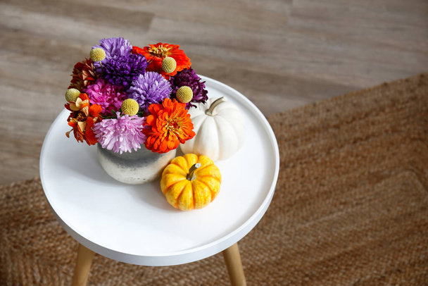 Empty apartment with minimalistic style interior, coffee table with autumnal bouquet in a vase and mini pumpkins on foreground. Copy space for text, background, close up. - Photo, Image