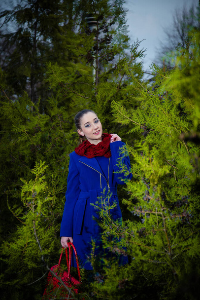 Nuori tyttö neulottu snood huivi punainen laukku sininen takki. Naisten syksyn ja talven vaatteet ja asusteet käsite. - Valokuva, kuva
