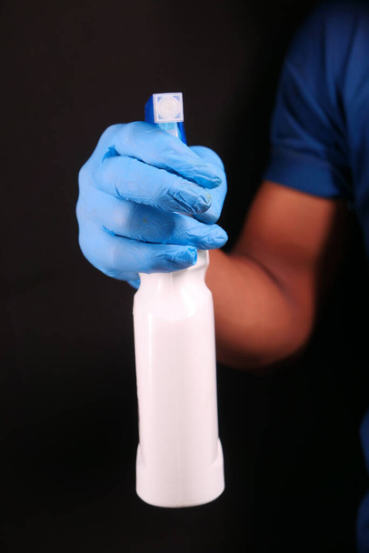 Hand in blauen Gummihandschuhen mit Sprühflasche  - Foto, Bild