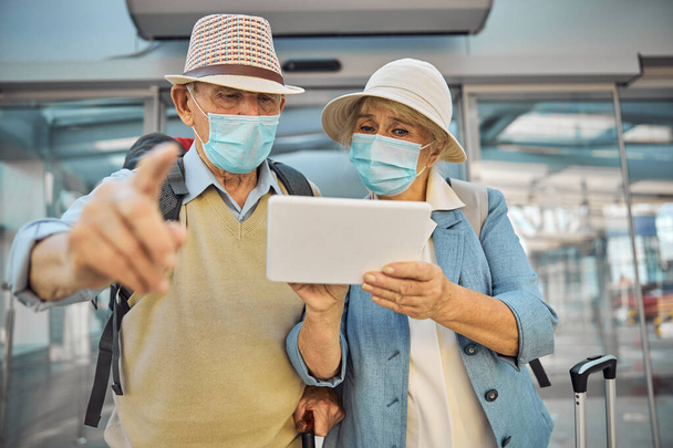 Viajeros mayores caucásicos usando su gadget en el aeropuerto - Foto, imagen