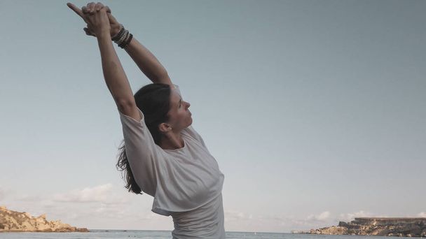 Mavi gökyüzüne karşı yoga yapan beyaz tenli bir kadın. - Fotoğraf, Görsel