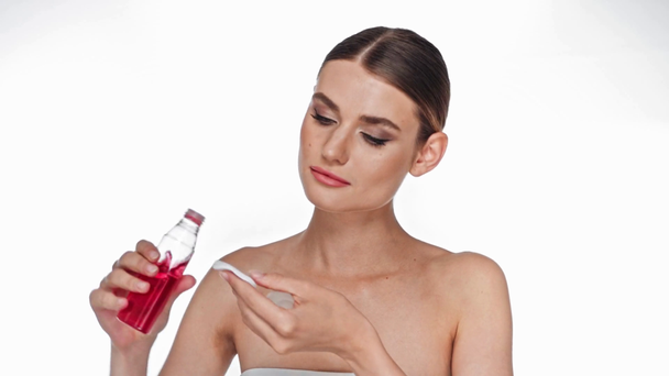Jeune femme adulte appliquant de l'eau tonique sur le visage avec coton isolé sur blanc - Séquence, vidéo
