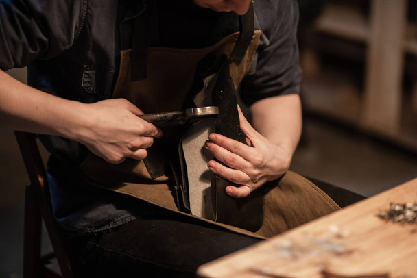 un zapatero hereditario hace zapatos de cuero en el taller familiar. - Foto, Imagen