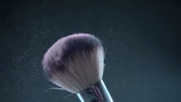 Vista ravvicinata di fibre di pennello cosmetiche spruzzando con polvere sul nero - Filmati, video