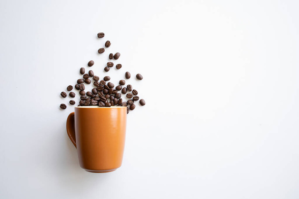 Kahverengi bardakta kahve çekirdekleri beyaz masa arkasında. Üst Manzara. Metin için boşluk - Fotoğraf, Görsel