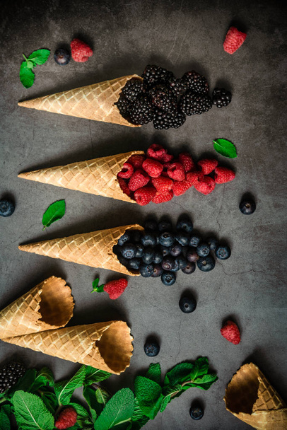 Fresh berries in waffle cones on dark stone background, top view. Concept healthy food and desert. - Foto, Imagem