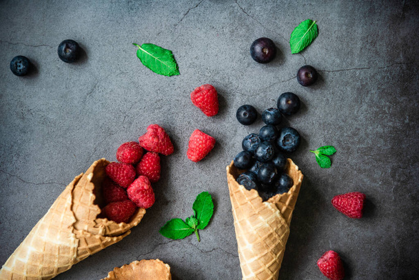 Fresh berries in waffle cones on dark stone background, top view. Concept healthy food and desert. - Foto, imagen