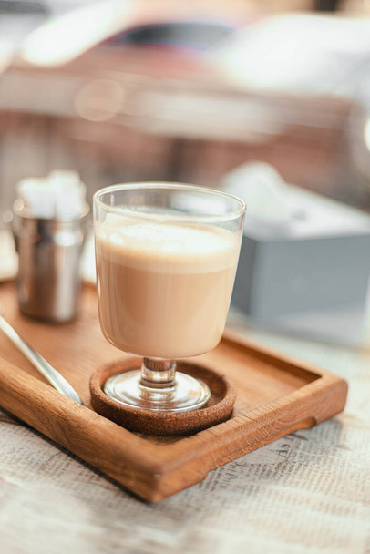Horká raf káva ve skleněném stylovém šálku na dřevěné desce v pouliční kavárně. Svislá orientace fotografie - Fotografie, Obrázek