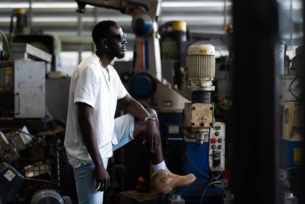 Portrait photo young stylish black man in a white T-shirt and glasses in old factory. Street photo. african american people. - Foto, afbeelding