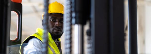 Warehouse man worker driver forklift. warehouse worker driver stacking card boxes by forklift in warehouse store. African American black people. - 写真・画像