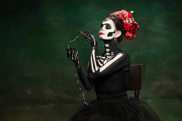 Young girl in the image of Santa Muerte, Saint death or Sugar skull with bright make-up. Portrait isolated on studio background. - Fotó, kép
