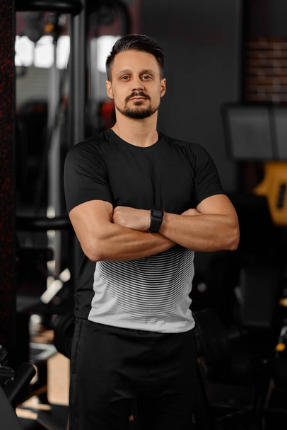 Portrait of personal trainer in sports outfit in fitness center gym standing strong - Photo, Image
