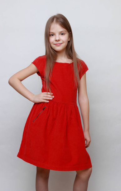 Elegant emotional kid is posing and dancing on a camera. Little girl ia a red dress. - Zdjęcie, obraz