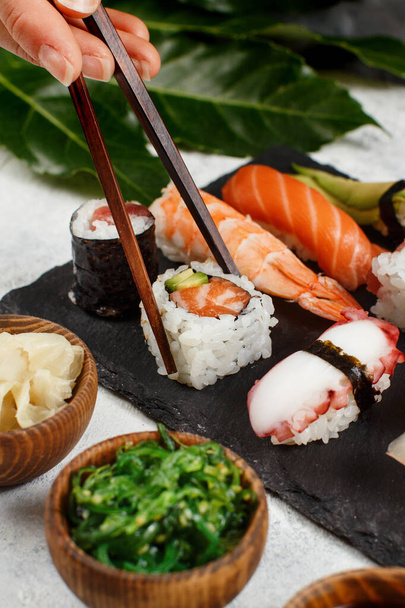 Lähikuva käsi ottaen rulla syömäpuikot lautasella sushi bar - Valokuva, kuva