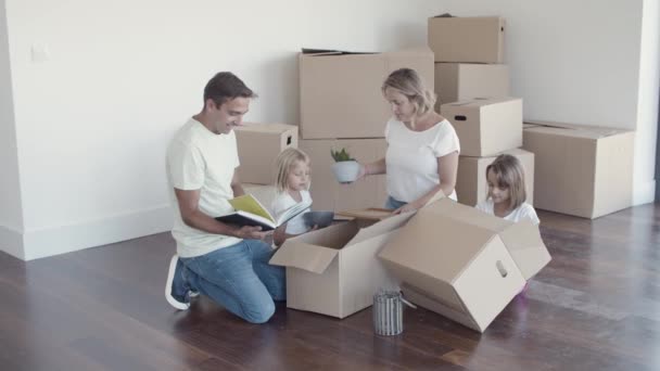 Fröhliche Familie mit Kindern beim Auspacken in neuer Wohnung - Filmmaterial, Video