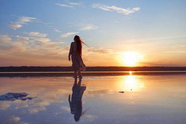 Kaunis nuori nainen lentävät punaiset hiukset meren rannikolla auringonlaskun aikaan - Valokuva, kuva