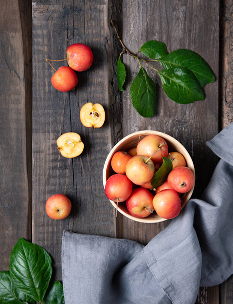juicy mini apples in a bowl with linen towel on a old wooden background. Rustic style and top view - Foto, afbeelding