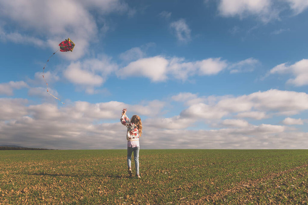 cute girl running with kite in green field in sunny autumnal day - Valokuva, kuva