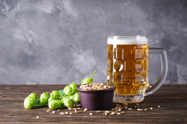 Hops and glass of light beer on wooden background, place for text. - Photo, Image