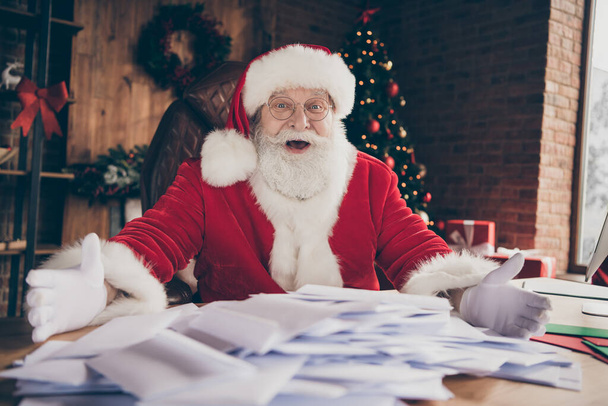 Crazy santa claus amazed impressed many receive wish list letters showing sit table wear cap headwear in house indoors with christmas x-mas lights decoration - Foto, Imagem