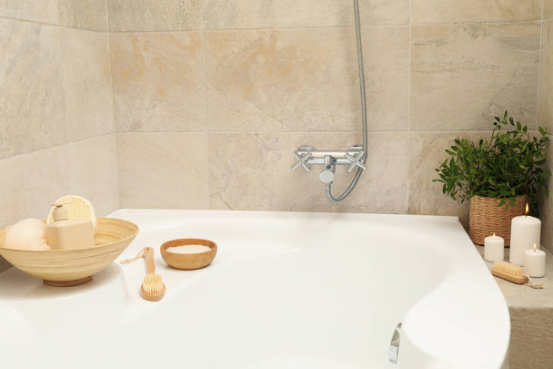 Bath with personal hygiene accessories in light beige bathroom - Photo, Image