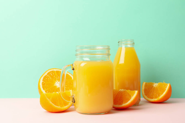 Słoiki szklane z sokiem pomarańczowym na tle mięty - Zdjęcie, obraz