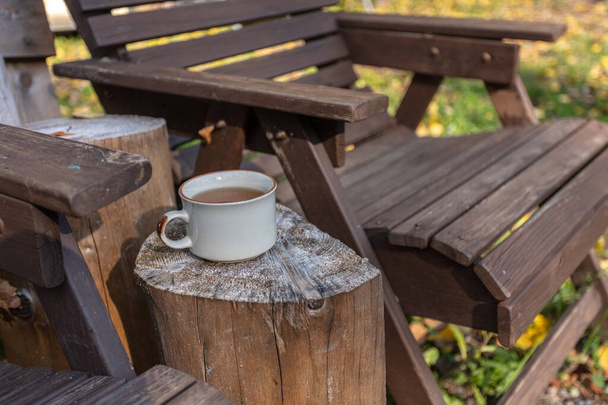 Cup with tea and wooden chairs, outdoors - Photo, Image
