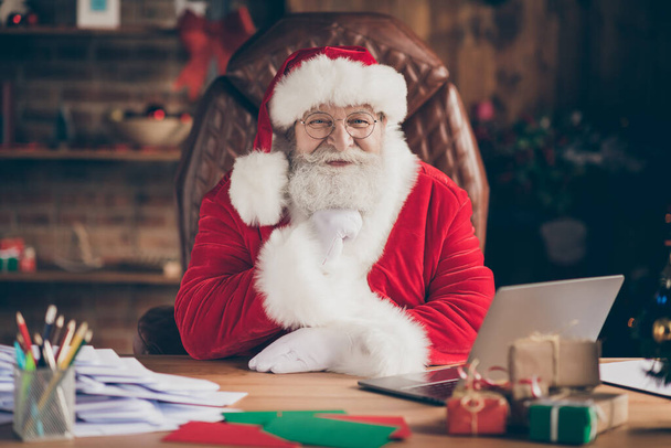 Portrait of positive fairy dream santa claus sit table in x-mas christmas newyear ornament tinsel house indoors touch beard ready answer wish list letter - Foto, Imagem