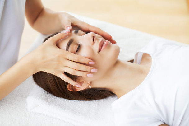 Mladá žena si užívá masáž obličeje v lázeňském salonu - Fotografie, Obrázek