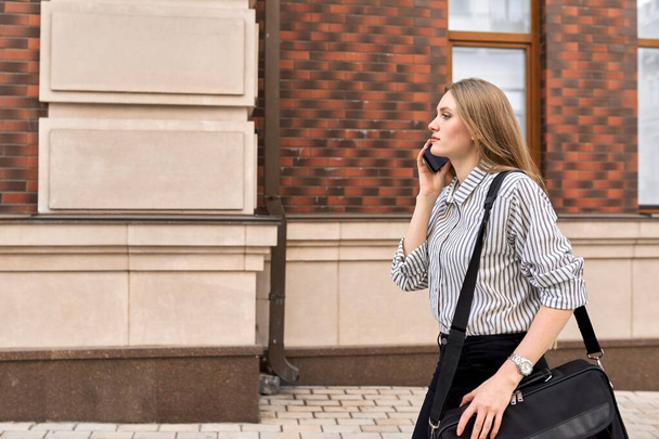Young business woman walking with cellphone, profile view copy space - Photo, Image