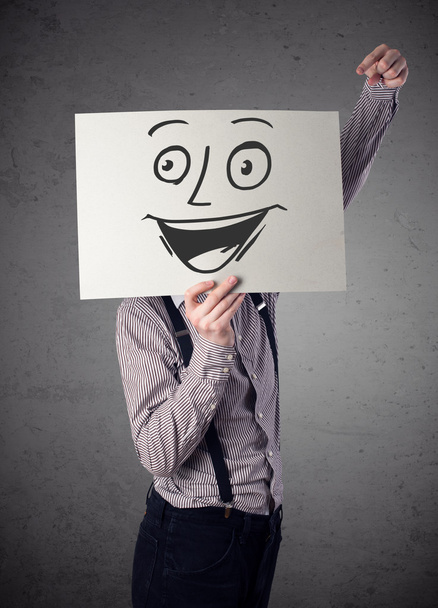 Businessman holding a cardboard with smiley face on it in front  - Foto, Imagen