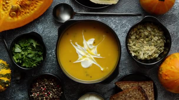Delicious pumpkin soup with cream, seeds, bread and fresh herbs in elegant ceramic black bowl - Footage, Video