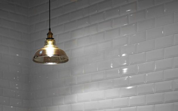 Enfoque suavemente de iluminar lámpara de techo de vidrio dorado con azulejos blancos borrosos fondo de pared en estilo vintage, concepto de decoración de interiores para el hogar - Foto, imagen