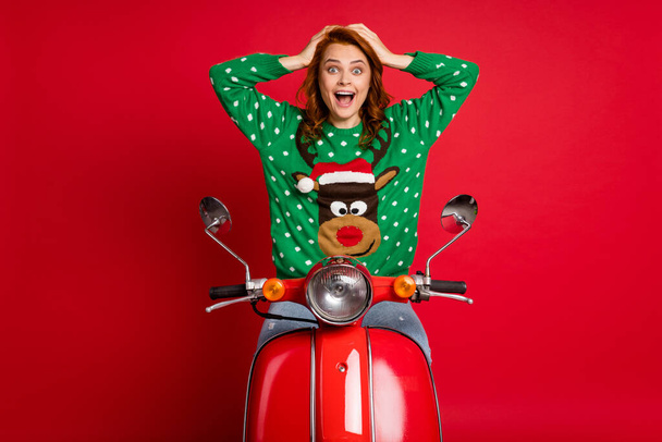 Photo portrait of shocked biker holding head with hands wearing ugly green reindeer sweater isolated on vivid red colored background - Foto, immagini