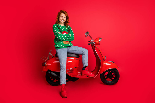 Photo portrait of confident biker sitting on scooter with folded arms wearing ugly green sweater isolated on vivid red colored background - Foto, imagen