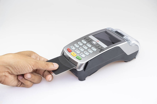 Κοντινό χέρι του ανθρώπου χρησιμοποιώντας το μηχάνημα σάρωσης πιστωτικών καρτών εισάγοντας κωδικό πιστωτικής κάρτας για να πληρώσει online ψώνια στο λευκό πάτωμα του τραπεζιού - Φωτογραφία, εικόνα