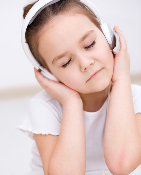 klein meisje is genieten van muziek met behulp van de hoofdtelefoon - Foto, afbeelding
