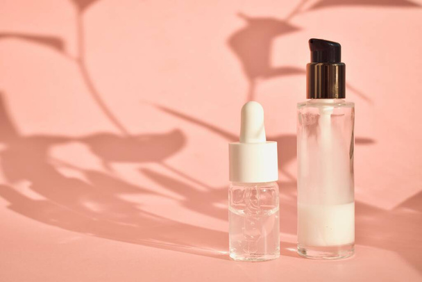Aceites aromáticos cosméticos en frascos con pipeta sobre fondo rosa con sombra. El concepto de eco-cosmética natural. - Foto, imagen
