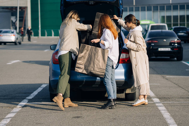 Mujeres jóvenes en el coche con bolsas de compras - Foto, imagen